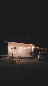 a white barn with lights on the side of it at night at refugio lonconao in Futaleufú