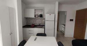 a kitchen with a table and a white refrigerator at Accarezza in Villa Carlos Paz