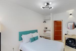 sypialnia z białym łóżkiem i lustrem w obiekcie Blooming Hideaway @ Cadetes 303 w mieście Meksyk