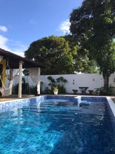 a swimming pool in a yard with a white wall at Village por do sol in Aracaju