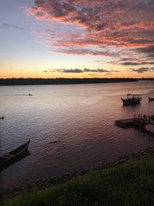 a sunset over a body of water with two boats at Village por do sol in Aracaju