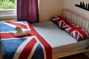 a bed with a red white and blue blanket and a window at Saint James Backpackers in London