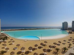 una gran piscina con sombrillas y la playa en Departamento Laguna del Mar, en La Serena