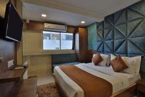 ガンディーナガルにあるHOTEL REST INNの大型ベッドとテレビが備わるホテルルームです。