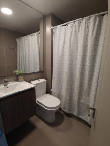 Un baño con inodoro, lavabo y cortina de ducha. en Departamento Laguna del Mar, en La Serena 18 fotos más