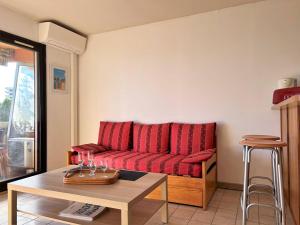 Appartement Le Lavandou, 1 pièce, 4 personnes - FR-1-251-202 في لو لا فاندو: غرفة معيشة مع أريكة حمراء وطاولة