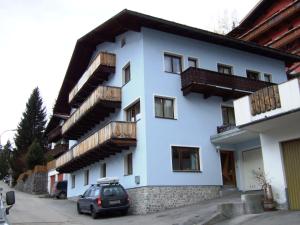 a white building with wooden balconies and a car parked in front at Haus Scherl in Sankt Anton am Arlberg