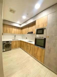 cocina con armarios de madera, lavadora y secadora en Narmiss Aparthotel, en Unaizah