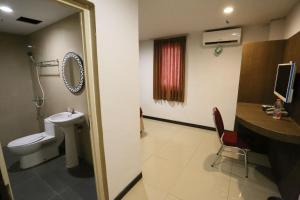 a bathroom with a toilet and a sink and a desk at New Z Suites in Sunggal