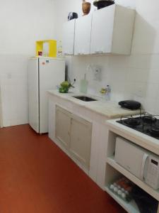 uma cozinha com armários brancos e um frigorífico branco em APT Praia Forte Passagem em Cabo Frio