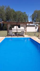 a swimming pool with two chairs and a pergola at Ecos del Valle in San Rafael