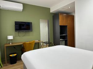 - une chambre avec un lit, un bureau et une télévision dans l'établissement Hôtel Exsel Créolia, à Saint-Denis