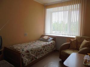 a bedroom with a bed and a couch and a window at Karelrepostrebsoyuz Hostel in Petrozavodsk