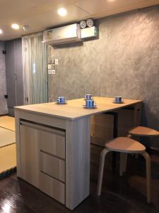 a counter with two stools and a table with cups on it at Espace Elastique B&B with contactless check-in in Hong Kong