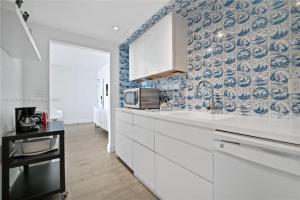 - une cuisine avec des placards blancs et du papier peint bleu et blanc dans l'établissement 1100 West South Beach Luxe Miami Condos by Joe Semary, à Miami Beach