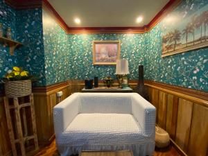 Silla blanca en una habitación con papel pintado azul en Casa Valle Verde, en Baguio