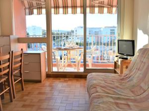 a room with a bed and a balcony with a television at Appartement Le Lavandou, 1 pièce, 4 personnes - FR-1-251-557 in Le Lavandou