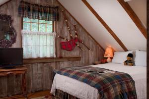 a bedroom with a bed and a tv in a attic at West Hill House B&B in Mad River Valley in Warren