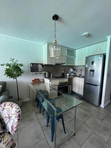 a kitchen with a table and a stainless steel refrigerator at Departamento Lagunamar con patio privado in Las Cruces