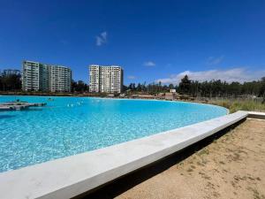 a large blue swimming pool with buildings in the background at Departamento Lagunamar con patio privado in Las Cruces