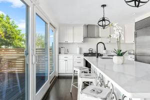 a kitchen with white cabinets and a large window at Poolside Chic by the Sea - Ocean Bay Park, NY in Ocean Beach