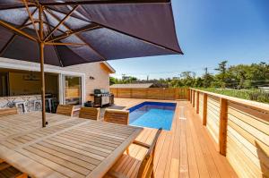 a deck with an umbrella and a swimming pool at Poolside Chic by the Sea - Ocean Bay Park, NY in Ocean Beach