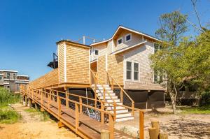 a house with a wooden deck in front of it at Poolside Chic by the Sea - Ocean Bay Park, NY in Ocean Beach