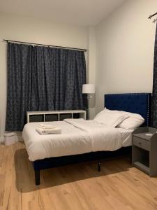 1 dormitorio con 1 cama con cabecero azul y ventana en Spacious for groups 8mi from NYC, en Newark