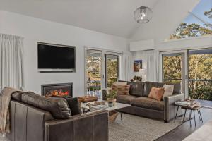 a living room with two leather couches and a fireplace at Braeside, Kangaroo Valley in Kangaroo Valley