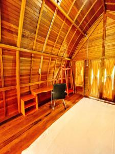 SinapuranにあるANARA VILLA SAMOSIR MANAGED BY 3 SMART HOTELの木製の壁の客室で、椅子が備わります。