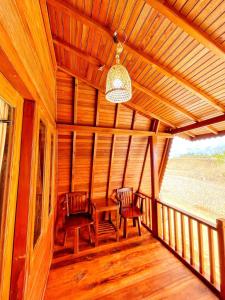 um alpendre de madeira com duas cadeiras e uma mesa sobre ele em ANARA VILLA SAMOSIR MANAGED BY 3 SMART HOTEL em Sinapuran