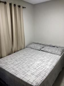 - un lit blanc dans une chambre avec des rideaux dans l'établissement Apartamento no Atalaia, à Salinópolis