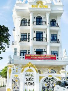 een wit gebouw met een bord ervoor bij Hotel Quốc Hương in Chợ Phước Hải