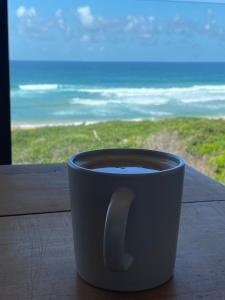 una taza de café sentada en una mesa frente a una ventana en Marien Beach House en Glentana