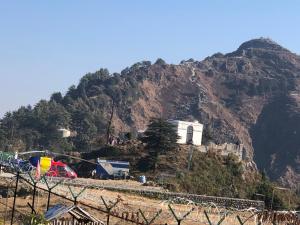 a hill with a house and a mountain at Shivoham valley view camps in Mussoorie