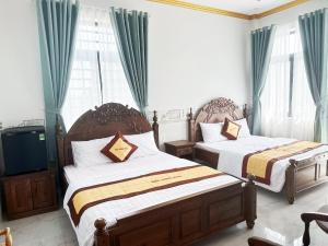 sypialnia z 2 łóżkami, telewizorem i oknami w obiekcie Hotel Quốc Hương w mieście Chợ Phước Hải