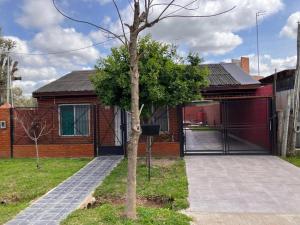 una casa con un árbol delante de ella en Casa quinta El Descanso en General Rodríguez