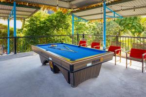 una mesa de billar en un patio con sillas rojas en Tropical retreat Homestay, en Cat Ba