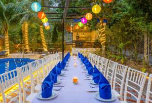 una mesa larga con servilletas azules y sillas junto a una piscina en Tropical retreat Homestay, en Cat Ba