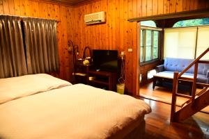 埔里鎮的住宿－佳園渡假山莊，一间卧室配有两张床、一张沙发和一台电视