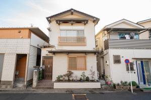 uma casa branca com uma porta castanha e alguns edifícios em 一戸建民泊 Tokyo St-ar House 東京星宿 em Tóquio