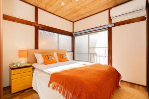 1 dormitorio con 1 cama con almohadas de color naranja y ventana en 一戸建民泊 Tokyo St-ar House 東京星宿 en Tokio