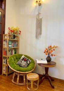 une chaise verte dans une chambre avec une table dans l'établissement Homestay Ahihi Đà Lạt, à Đà Lạt
