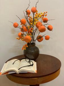 un livre sur une table avec un vase avec des oranges dans l'établissement Homestay Ahihi Đà Lạt, à Đà Lạt
