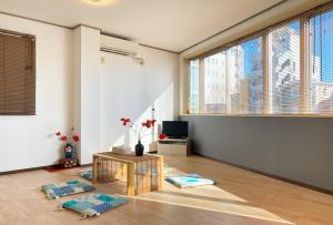 ein Wohnzimmer mit einem Tisch und einigen Fenstern in der Unterkunft Mitomi Home 4F in Tokio