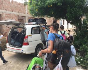 un grupo de personas de pie junto a un coche con equipaje en The Highvill Home Stay en Khajurāho