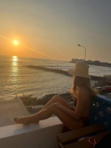 a woman sitting on a bench watching the sunset at La mejor Vista al Point de la Playa San Bartolo in San Bartolo