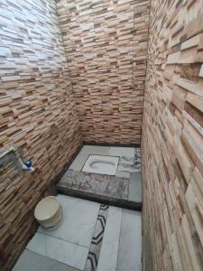 ein Badezimmer mit Toilette und einer Ziegelwand in der Unterkunft Nagpur Tuljai Villa Homestay in Khāpri