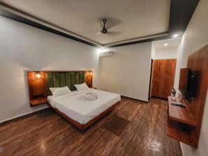 a bedroom with a large white bed and wooden floors at Rashiva Resort in Arambol