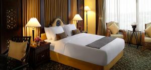 a hotel room with a large bed and a chair at โรงแรม ซี.เอส. ปัตตานี in Ban Ru Sa Mi Lae